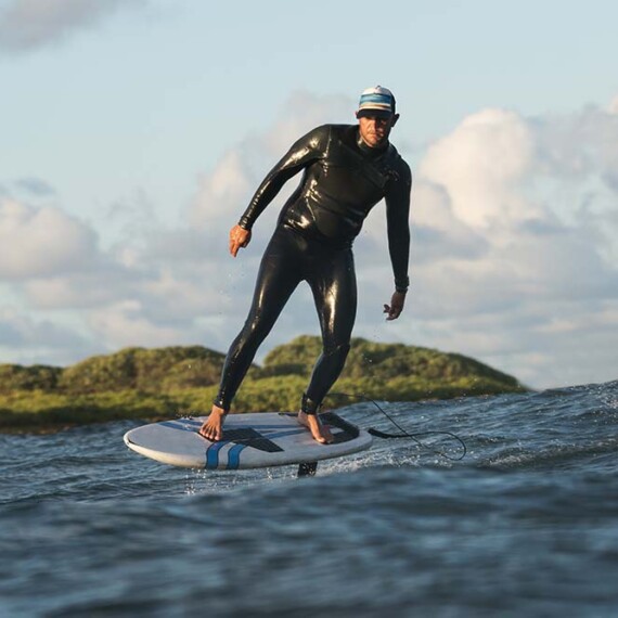 A man in a wetsuit skillfully rides a surfboard on a vibrant ocean wave.