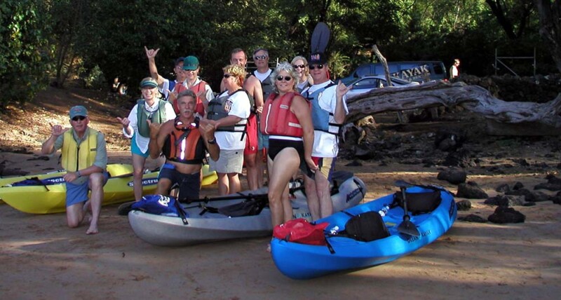 A cheerful group of people stands in front of their kayaks, capturing a moment of camaraderie by water.