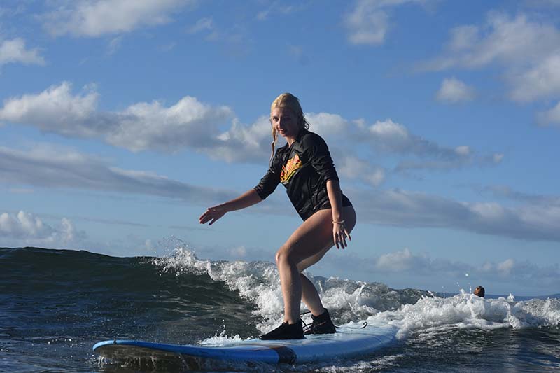 A lady surfing on a board in Maui ocean, capturing the essence of adventure and joy of riding the waves.