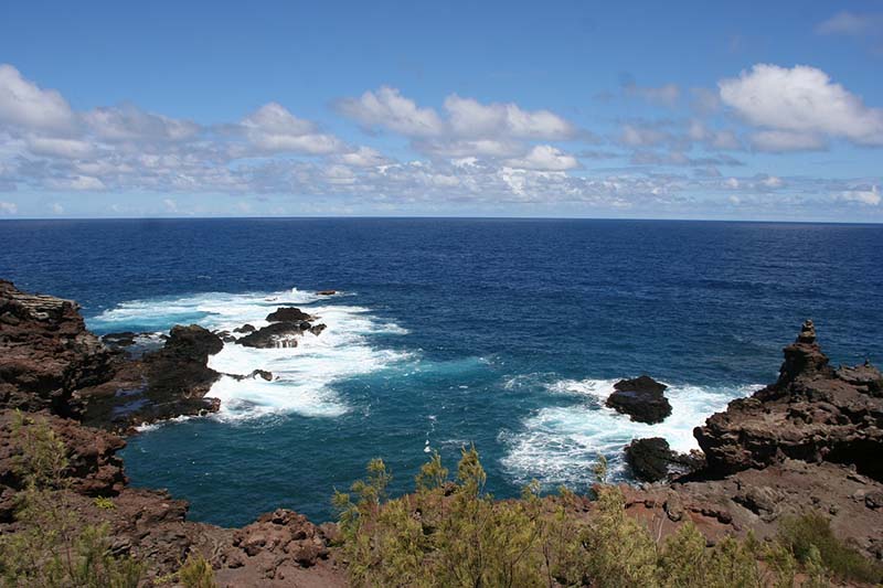 A serene blue ocean with gentle waves rolling towards the shore under a clear sky.