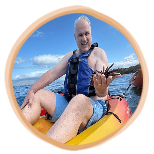 A man in a kayak proudly holds a see flower, showing off his catch during day on water.