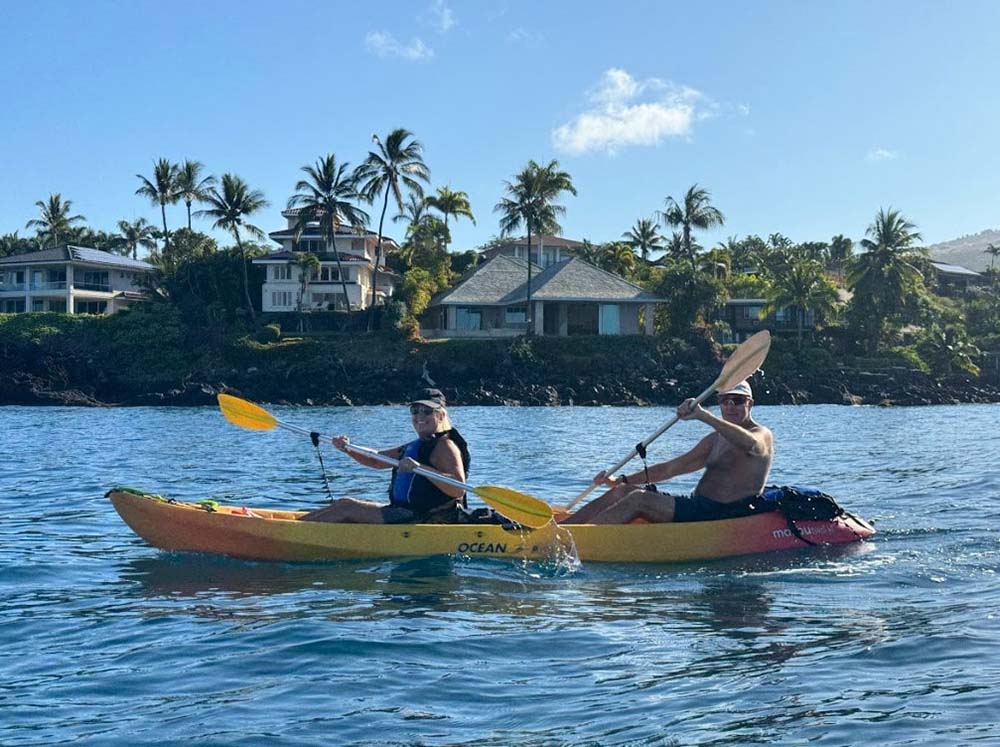 Man and woman enjoy the Maui kayaking tours in Maui beautiful greenish water