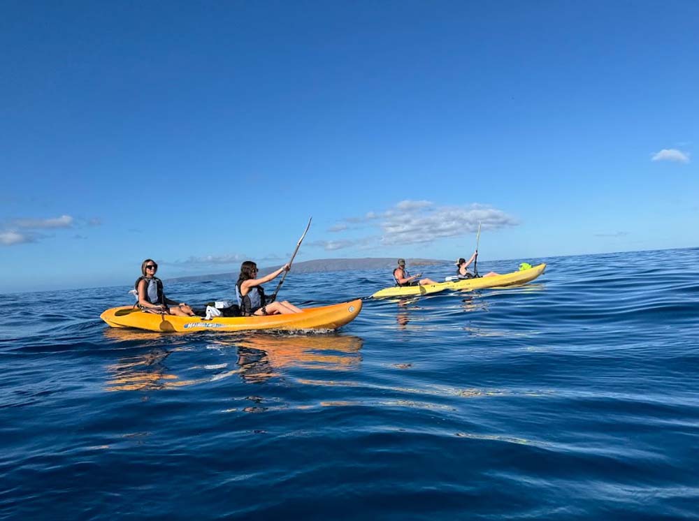Families kayaking together on calm blue waters in Maui, enjoying one of the Top 5 Family-Friendly Water Tours in Maui under sunny skies.