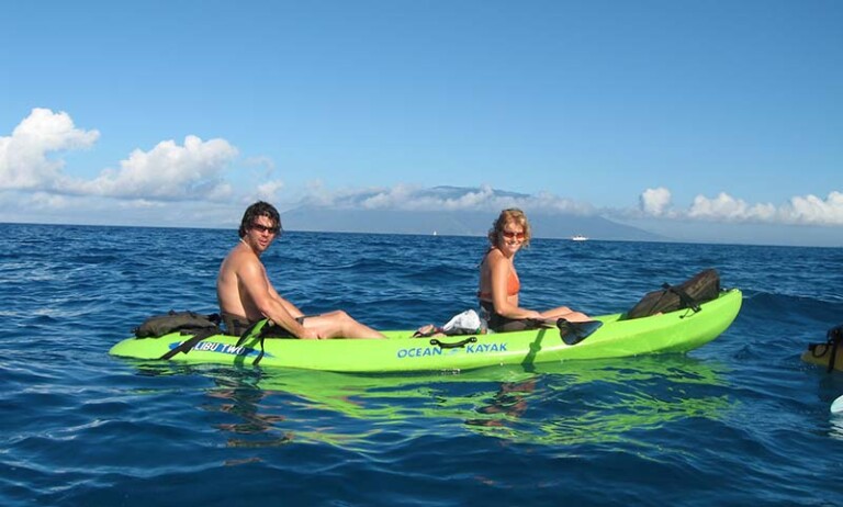 A couple kayaking on the clear blue ocean during Maui in October, enjoying warm weather and outdoor adventures.
