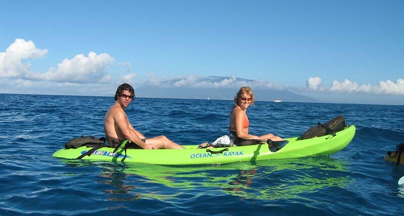 A couple kayaking on the clear blue ocean during Maui in October, enjoying warm weather and outdoor adventures.